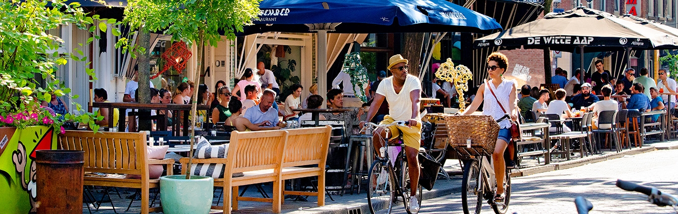 Couple cycling in summer through Witte de Withstraat Rotterdam