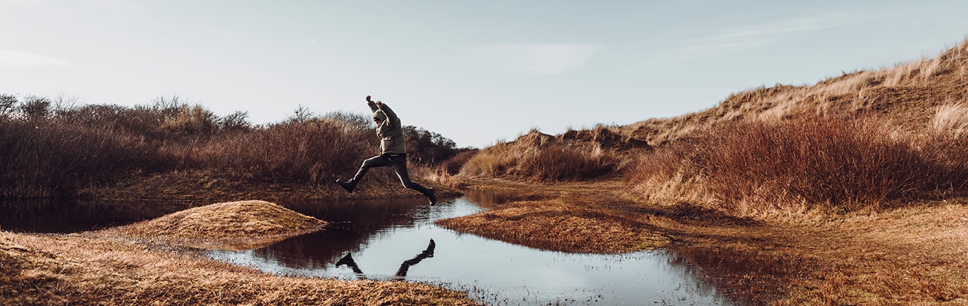 Man jumps over a puddle on Wadden Island Texel